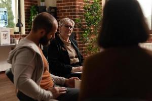 Close up of psychiatrist having conversation with alcoholic people at aa meeting photo