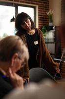 Woman smiling and talking about recovery with people at aa therapy meeting photo