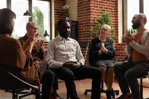 Group of people at aa meeting applauding success of man photo