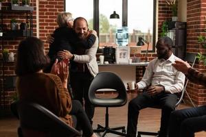 psicólogo dando un abrazo al hombre después de compartir el progreso de la recuperación con las personas en una reunión foto