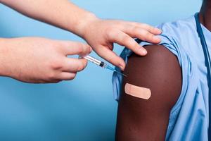 Close up of hands with syringe and needle vaccinating arm photo