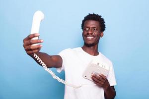 African american man pretending to take selfie on old landline phone photo