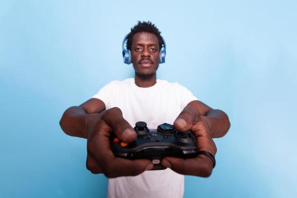 Person playing video games with controller on computer. Player using  joystick and wearing headphones to play online game on monitor. Modern man  using gaming equipment to have fun. Stock Photo