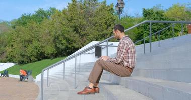 young male businessman sitting on the stairs outdoors working with laptop photo