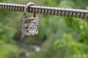 Old padlock of gray color with spots from rust. Vintage padlock on a green background and place for text photo