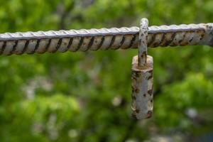 Old padlock of gray color with spots from rust. Vintage padlock on a green background photo