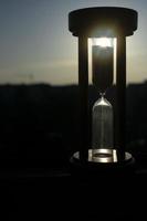 Hourglass close-up on a background of blue sky with clouds. photo