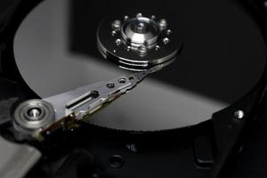 disco duro del disco duro de la computadora y herramientas de reparación con efecto espejo. primer plano, macro, sobre un fondo negro. foto