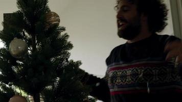man versiert kerstboom met lichtjes video