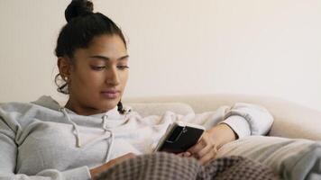 Mujer en el sofá desplazándose y escribiendo en el teléfono inteligente video