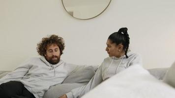 donna e uomo sul divano che guardano in una rivista video
