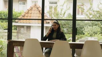 mulher sentada à mesa levantando-se e entrando na sala enquanto liga com o smartphone video