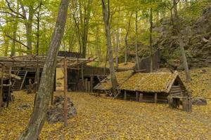 Antigua cabaña de madera en el bosque de otoño sembrado de hojas foto