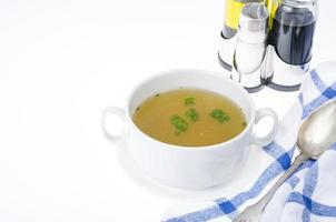 Transparent meat broth with herbs in white plate photo