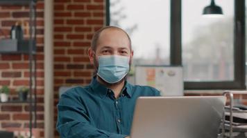 Portrait of business man wearing face mask and using laptop video