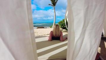 Mujer rubia descansando en una cabaña de playa resort tropical video