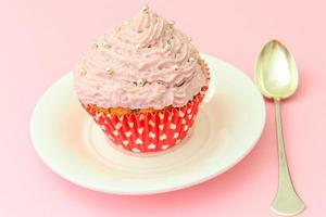 pastel con crema, cupcake sobre fondo rosa. foto