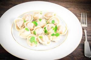 Tasty Homemade dumplings, Russian Pelmeni on Wood Background. photo