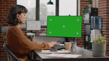 Mujer que trabaja con pantalla verde horizontal en el monitor