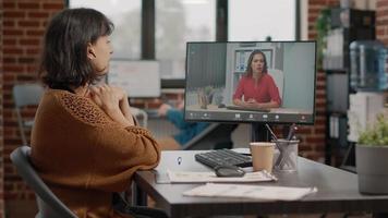 Employee waving at video call camera to talk to manager