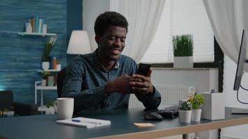 Positive authentic black african american man smiling while using a smartphone
