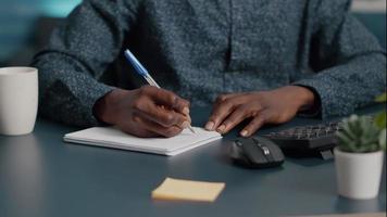 Primer plano de manos del hombre negro afroamericano tomando notas en el bloc de notas con un bolígrafo video