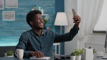 Authentic happy african american man taking a selfie in the living room to share it on social media video