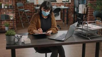 Mujer comparando la información de los gráficos desde el portapapeles y el portátil video