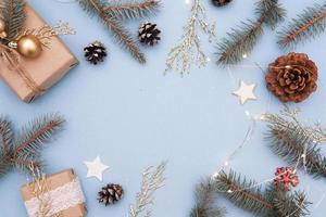 endecha plana de navidad. concepto foto regalo de navidad, año nuevo. abeto y ramitas doradas, adornos, guirnaldas sobre un fondo azul. copia espacio