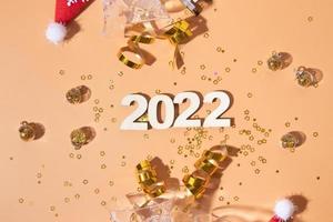 Festive new year flat lay with numbers 2022 and hard shadows with glasses and shiny decor photo