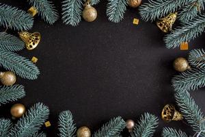 Top view Merry Christmas black background decorated with Happy New Year Christmas tree branches and baubles with copy space. Winter holiday card decoration festive fun concept, flat lay. photo