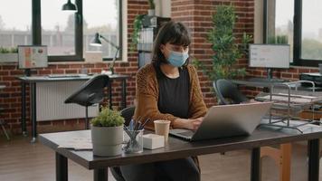 mujer de negocios, llevando, mascarilla, y, usar la computadora portátil video