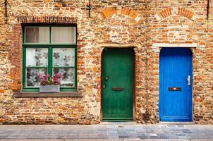 The facade of an old brick house with a window and two wooden doors photo