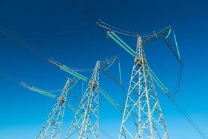 High voltage power lines with blue sky on the background, three electricity pylons photo