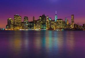 Manhattan skyline at night with colored reflections in water, New York, USA photo