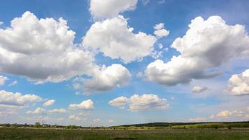 un campo con un cielo azul claro lleno de nubes blancas en el fondo en un clima soleado de verano sin viento ni lluvia.