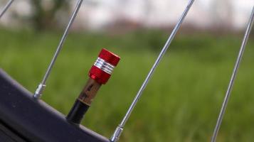 Bicycle red nipple. Detail of a used bicycle rim with valve stem and cover. Mountain bike tire. Bicycle wheel valve. photo