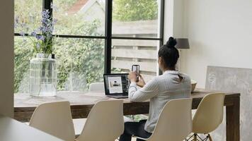 Woman sitting at table having video call with smartphone