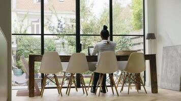 Woman sitting at table having video call with smartphone