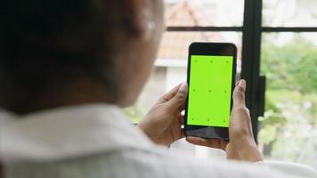 mujer sosteniendo smartphone con pantalla verde y conversaciones