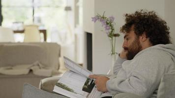 Man on couch reading magazine video