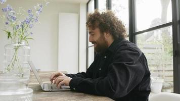 Hombre con videollamada vívida en la computadora portátil mientras escribe video