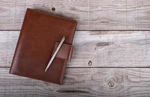 Leather businessman and pen diary on wooden background photo