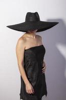 Standing woman wearing black suit and black hat, retro fashion photo