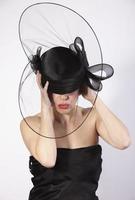 beautiful woman holding on black hat with hands, retro fashion photo