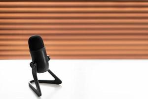 Black microphone on white table and blurry background.