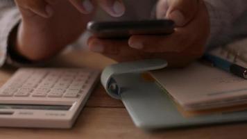 Close up hands of businessman chatting on mobile smartphone during working on the desk. video