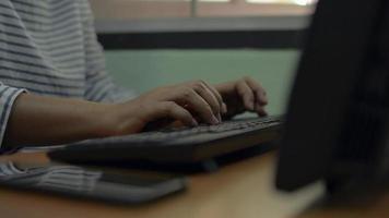 mujer escribiendo teclado de computadora y conectado al teléfono móvil con tecnología inalámbrica en el escritorio de trabajo.