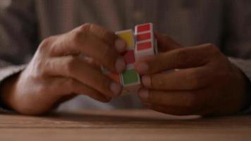 Cierre las manos del empresario resolviendo el rompecabezas del cubo de Rubik en el escritorio.