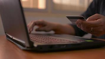 empresaria sosteniendo una tarjeta de crédito y escribiendo en el teclado de la computadora portátil para el pago en línea en casa. video